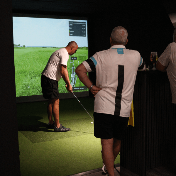 Group of adults playing golf on a trackman bay